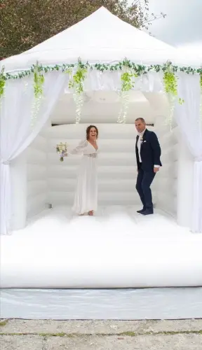 novomanželé se fotí na nafukovacím svatebním hradu, nevěsta drží květiny